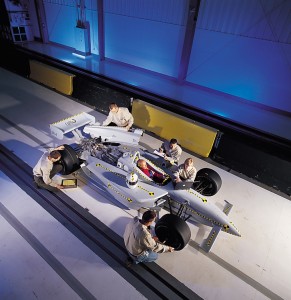 Technicians are shown prepping a race car for a barrier block test.